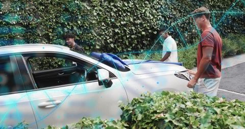 Young friends inspecting white sedan with blue towel on hood by ivy-covered wall
