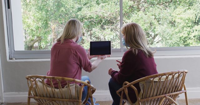 Women Using Tablet Wearing Face Masks in Bright Room - Download Free Stock Images Pikwizard.com