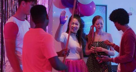 Diverse Friends Celebrating Birthday with Asian Woman in Pink Tutu under Neon Balloons