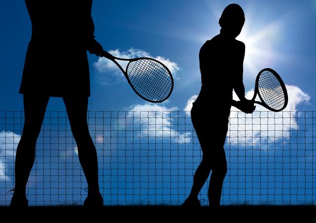 Silhouette of tennis player with rackets against sunny sky background