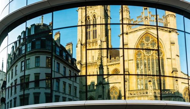 Curved glass reflecting gothic cathedral and mansard roof in golden light
