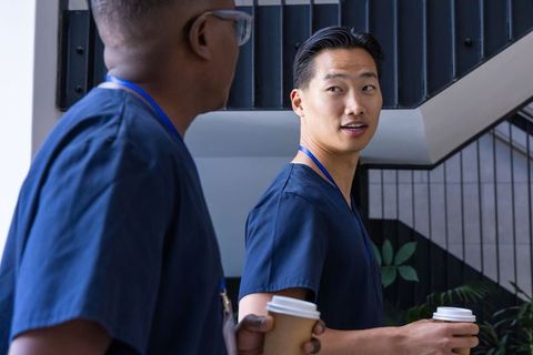 Diverse healthcare team walking up staircase holding coffee cups in navy scrubs