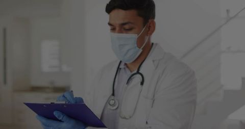 Doctor in clinic writing notes on clipboard with mask and stethoscope