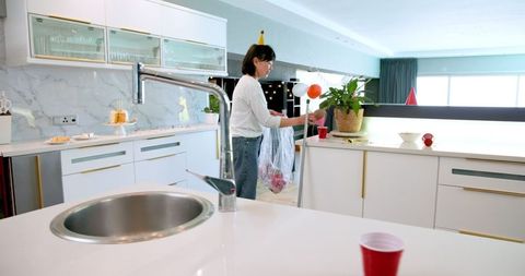 Senior Woman Cleaning Kitchen After Birthday Party