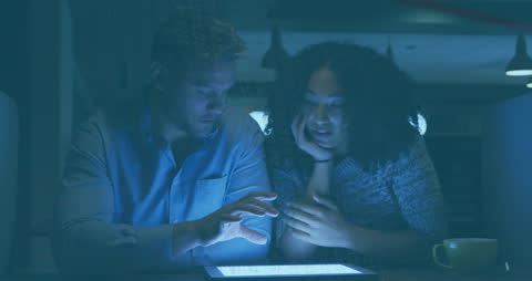 Colleagues Discussing Digital Innovations in Dimly Lit Office Setting