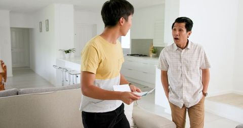 Young Man Discussing Paperwork at Home with Father