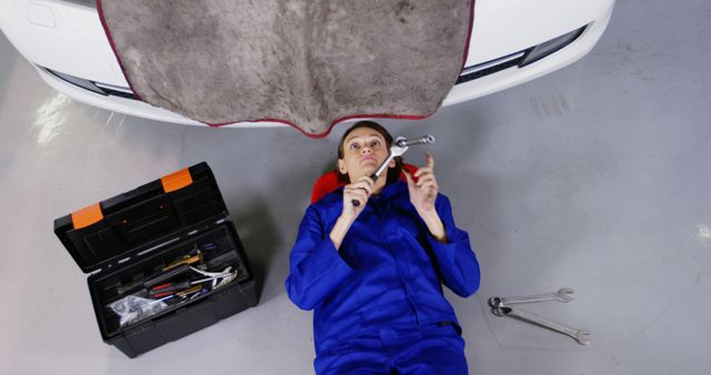 Female mechanic working under car assessing tools - Download Free Stock Images Pikwizard.com