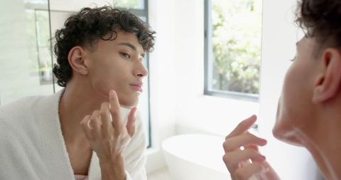 Young Man Practicing Skincare Routine in Luxury Bathroom