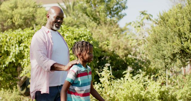 Smiling African American Man and Child Strolling in Lush Garden - Download Free Stock Images Pikwizard.com