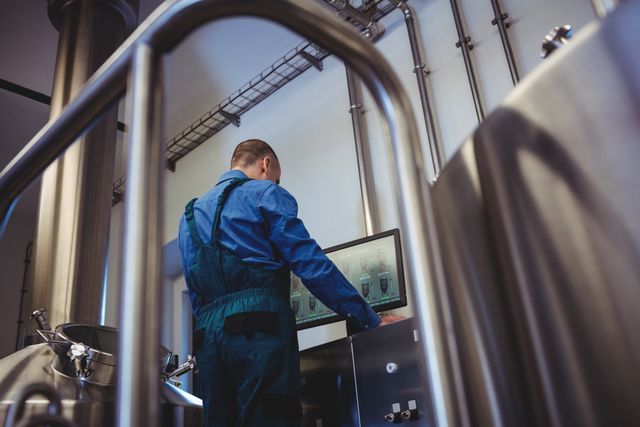 Low angle view of male manufacturer using computer at brewery