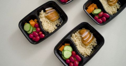Meal-prep bowls featuring glazed chicken, couscous and cucumber cherry tomato portions