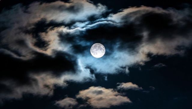 Full Moon Casting Pale Blue Halo Through Layered Clouds, Dramatic Nocturnal Sky