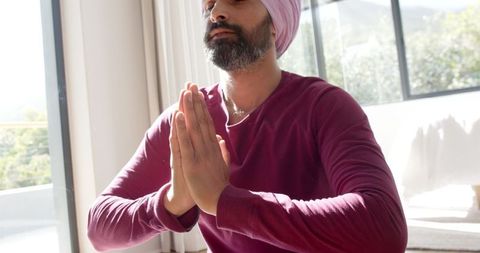 Man practicing meditation in sunlit living room