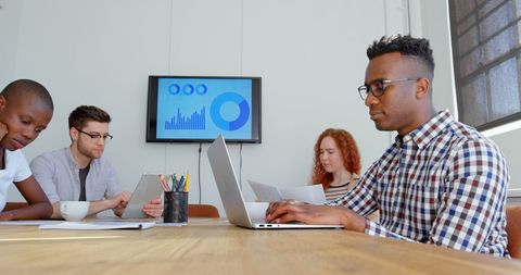 Diverse group of people engaging in teamwork, highlighting collaboration and use of technology. Perfect for showcasing a professional environment, corporate teamwork, tech in workspace, or business productivity themes.
