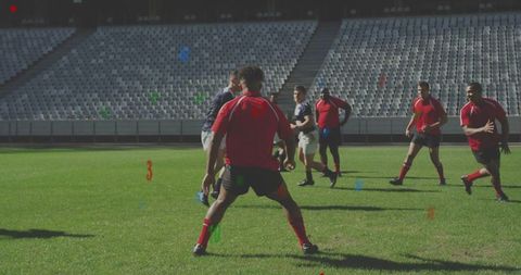 Red team defender closing down opponent with ball on sunlit rugby stadium field