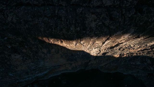 Sunlit band revealing textured rock strata on steep canyon cliff at golden hour