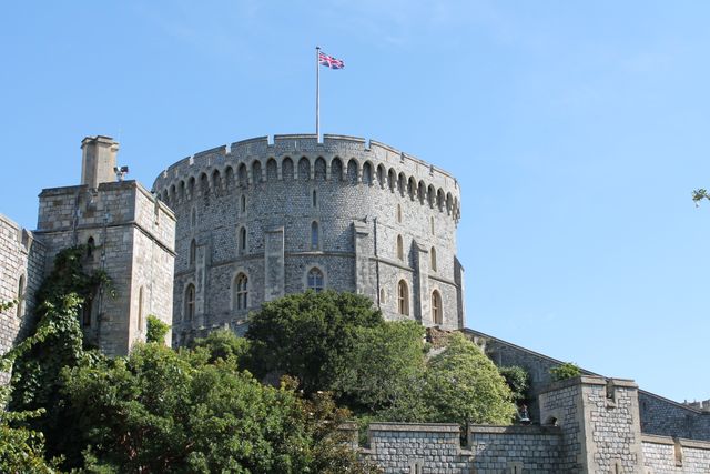 Evoke the charm of historic architecture with this image of a majestic stone castle tower crowned by a British flag. Perfect for illustrating tourism websites, travel brochures, and historical articles. Ideal for emphasizing British heritage and medieval architecture.
