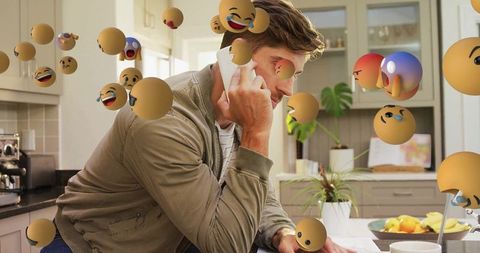 Man using Smartphone with Floating Emojis in Modern Kitchen