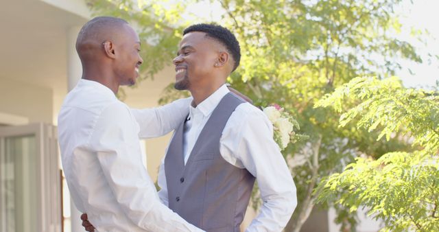 Happy diverse gay male couple dancing outdoors in the sun. Togetherness, relationship, love and domestic life, unaltered.