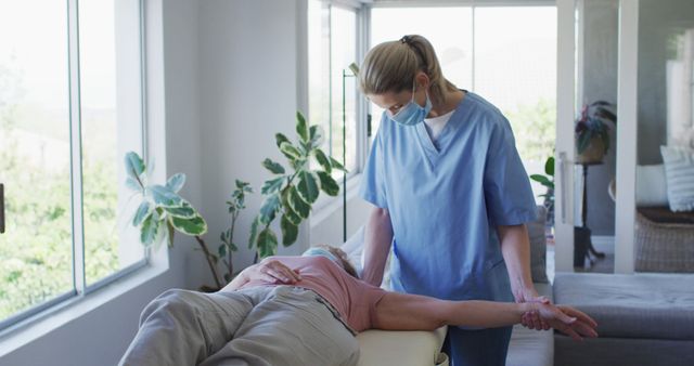 Physical therapist performs arm stretches with senior patient in home care setting. Ideal for depicting home healthcare, elderly rehabilitation, therapeutic exercises, and physical therapy sessions. Useful for resources related to senior care, healthcare practices, home treatment, and physical recovery.