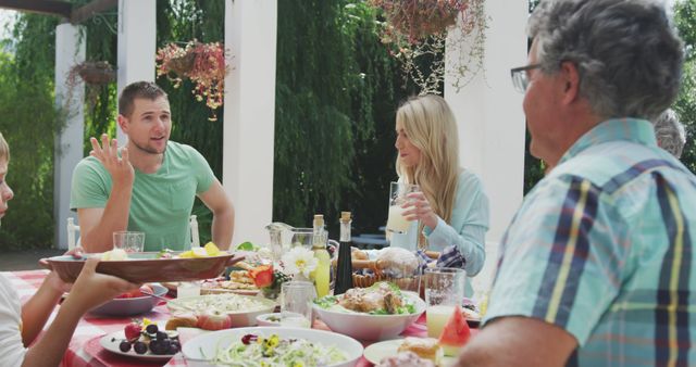 Happy caucasian family sitting at table in garden, eating dinner - Download Free Stock Photos Pikwizard.com