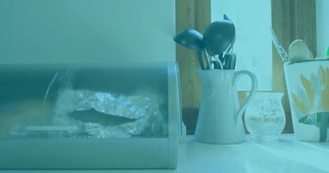 White ceramic jug holding kitchen utensils on minimalist countertop with bread box