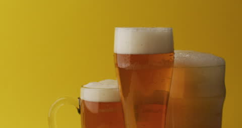 Refreshing Glasses of Beer with Bubbles on Yellow Background