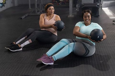 African american women exercising with medicine balls, training core strength and teamwork