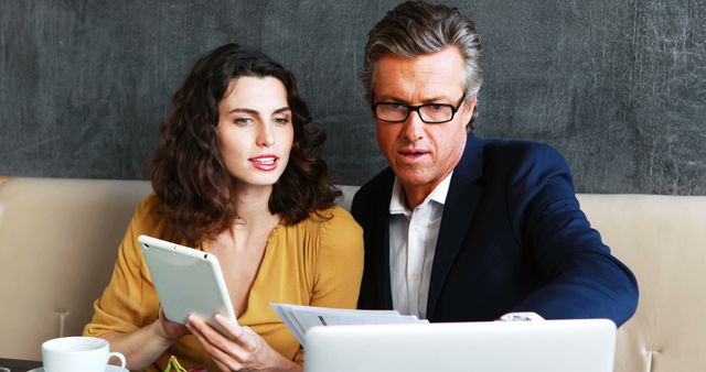 Business Professionals Discussing Work Over Laptop and Tablet in a Cafe - Download Free Stock Images Pikwizard.com