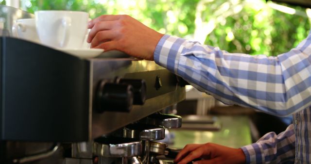 Image shows a barista using a professional coffee machine to prepare espresso in a coffee shop. Ideal for use in articles about barista skills, coffee brewing techniques, and the operation of a small business. Perfect for cafes or restaurants looking to promote their espresso and barista services.
