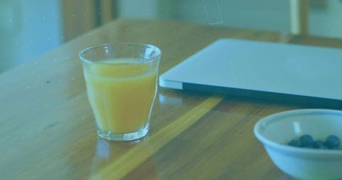 Cozy Workspace with Orange Juice and Laptop on Wooden Table