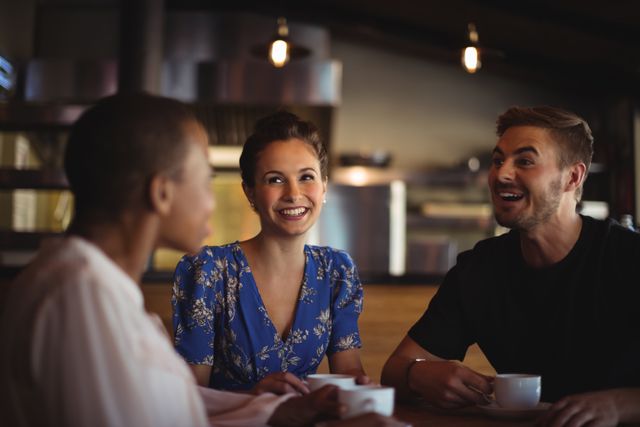 Happy friends interacting while having coffee in restaurant 