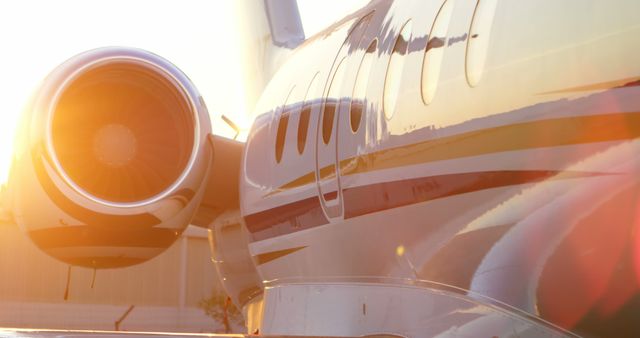 Close-up view of a private jet during sunset with warm light reflecting off its surface. Ideal for use in luxury travel, aviation industry promotions, business travel advertisements, and corporate brochures. Highlights elegance and exclusivity associated with private air travel.