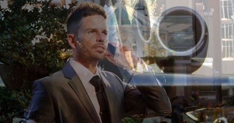 Businessman Communicating via Smartphone Near Reflective Building