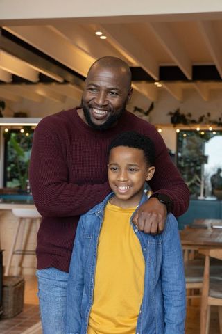 African american father and son sharing warm smile in cozy cafe with wood beams