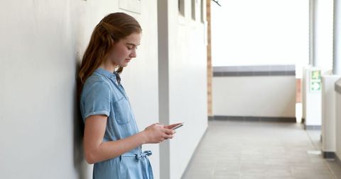 Teenage Girl Engaged with Smartphone in Bright Corridor - Download Free Stock Images Pikwizard.com
