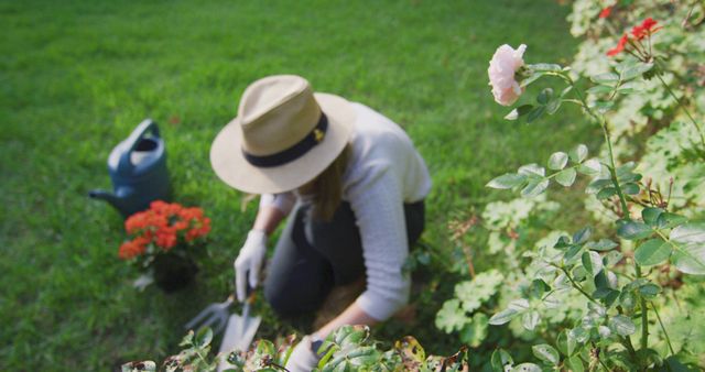 Caucasian woman wearing a hat and gardening gloves gardening in the garden. lgbt relationship and lifestyle concept