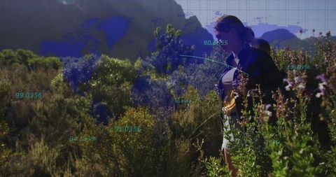 Surveying woman exploring mountainous scrubland with digital mapping overlay and data