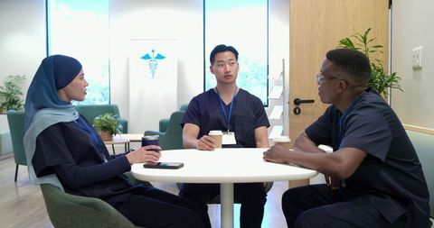 Multicultural healthcare team taking coffee break in modern staff lounge, casual teamwork