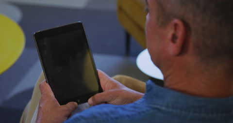 Businessman Using Tablet in Modern Office Over Shoulder Perspective