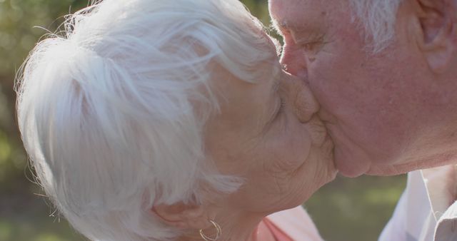 Happy senior caucasian couple kissing in sunny garden, slow motion. Senior lifestyle, togetherness, summer and nature, unaltered.