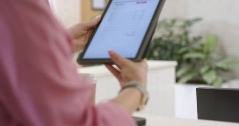 Receptionist holding tablet tapping digital document at modern minimalist office desk