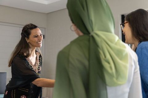 Female colleagues greeting and shaking hands in modern office meeting, diverse team