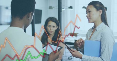 Business Women Collaborating on Tablets with Financial Charts Overlay