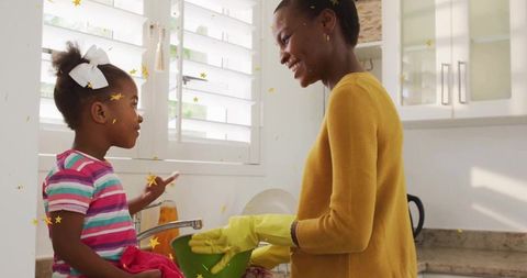 Mother and daughter washing dishes together in cheerful kitchen