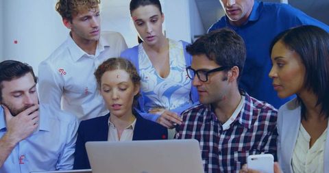 Seven Colleagues Collaborating Around Laptop During Team Meeting
