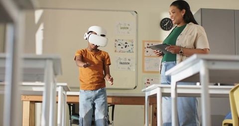 African American teacher guiding student using VR headset for immersive classroom learning