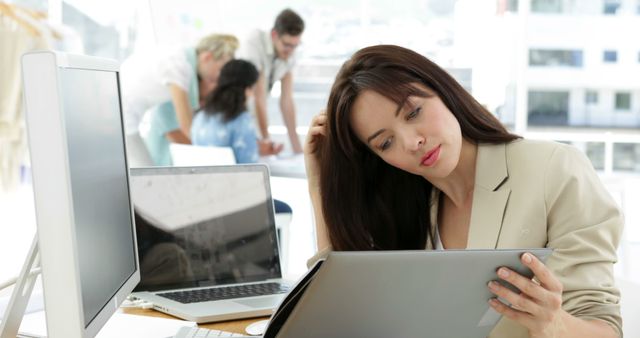 Woman working at her desk looking at folder in creative office