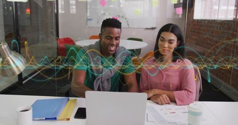 Young professionals collaborating over laptop with waveform data overlay in modern office