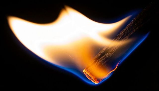 Burning Match Head Macro Showing White-Hot Core Blue-Edged Flame and Charred Wood Texture